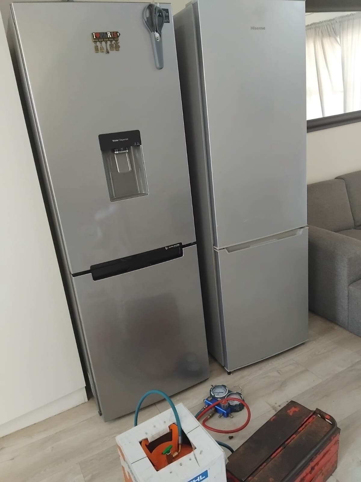 Samsung and Hisense fridges with gauges and refrigerant set up for a repair